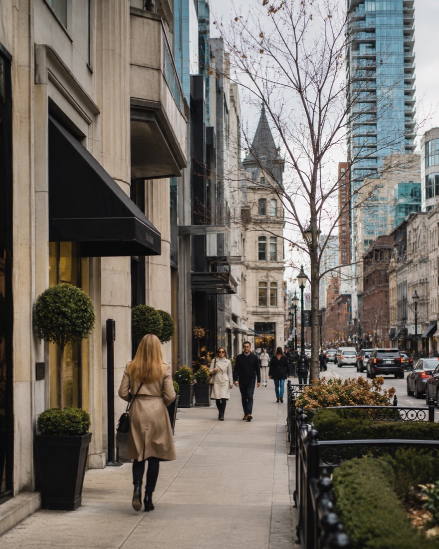 Yorkville, Toronto — Bloor-Yorkville streetscape with awning storefronts, Victorian turret, and downtown towers in the distance